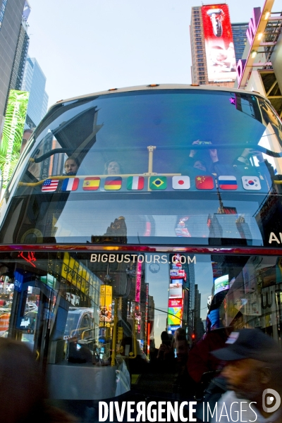 Retour a Manhattan # 01.Times Square, media city.Les enseignes lumineuses attirent la foule comme des papillons de nuit..Reflets des enseignes publicitaires  sur le pare brise d!un bus touristique a deux etages.