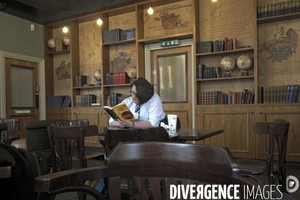 Edimbourg.Une lyceenne  en uniforme lit un livre de philosophie dans un cafe Starbucks
